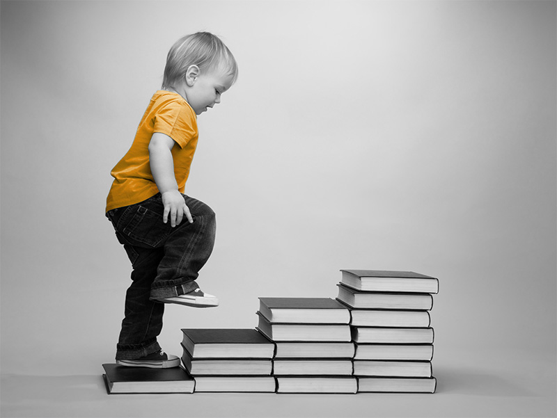 Child stepping up on stacked books